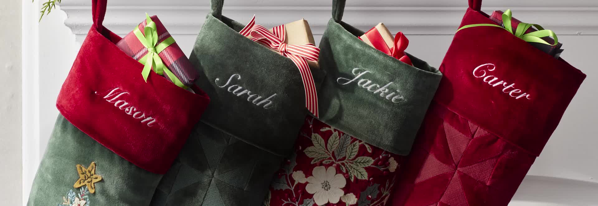 Holiday stockings filled with gifts above a decorated mantel